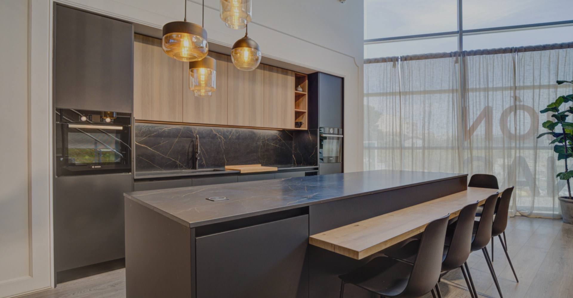 Cocina integral en gris grafito con frentes de madera, cubierta de piedra oscura y barra de madera