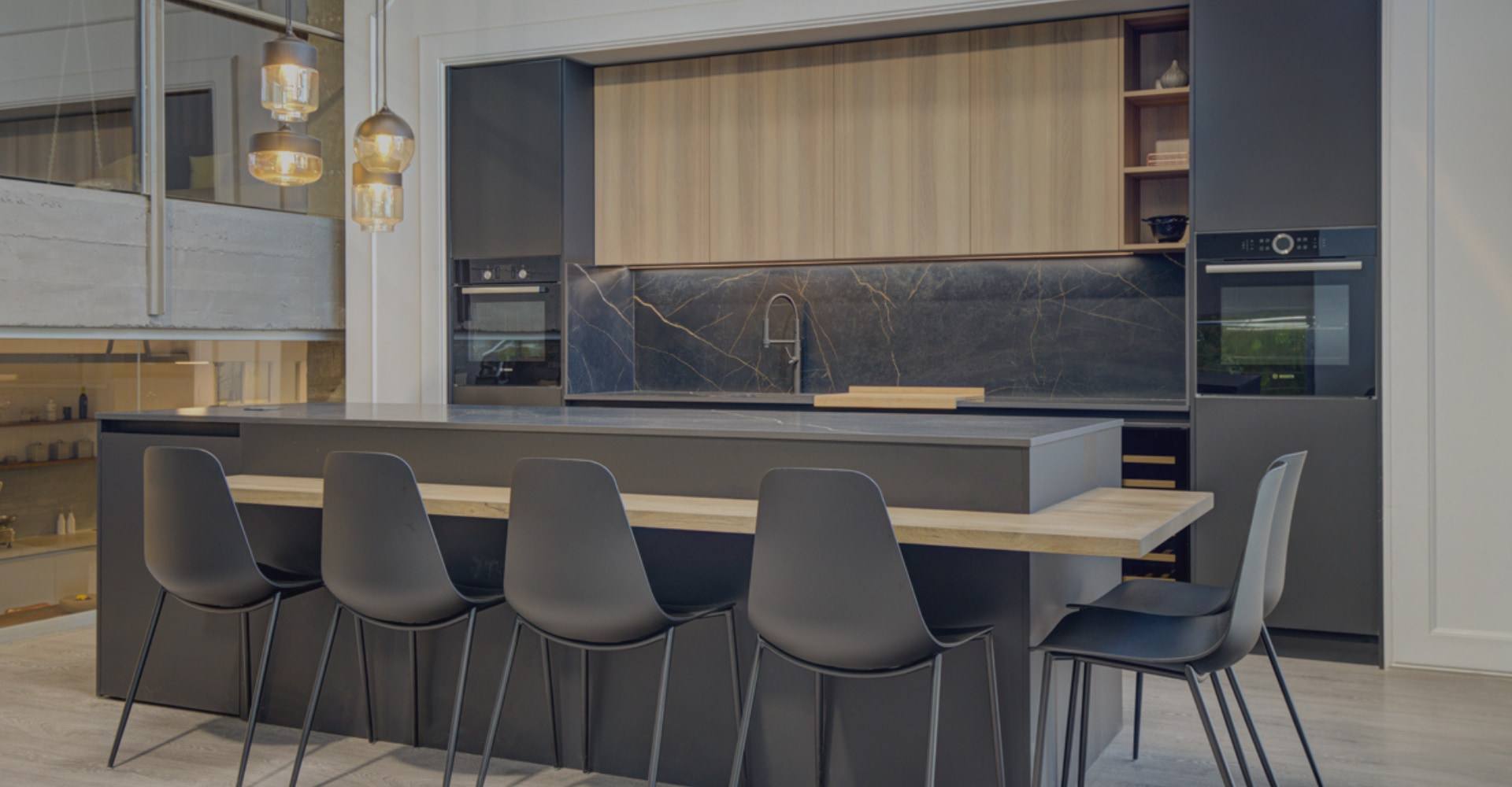 Cocina integral gris con isla, barra de madera y bancos